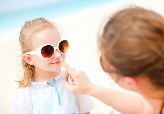Child sun protection showing proper sunscreen application and protective clothing for kids